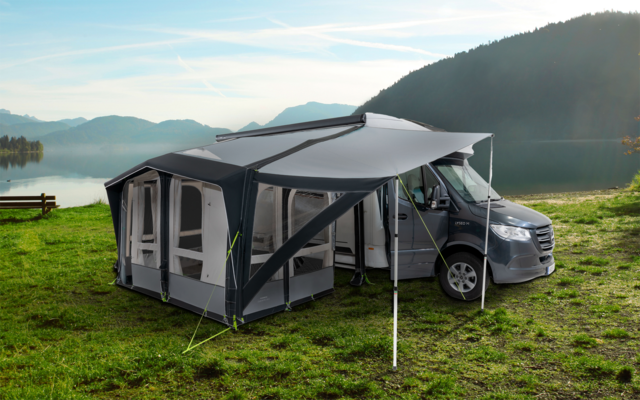 Wohnmobil mit angebautem Vorzelt auf einer Wiese neben einem See