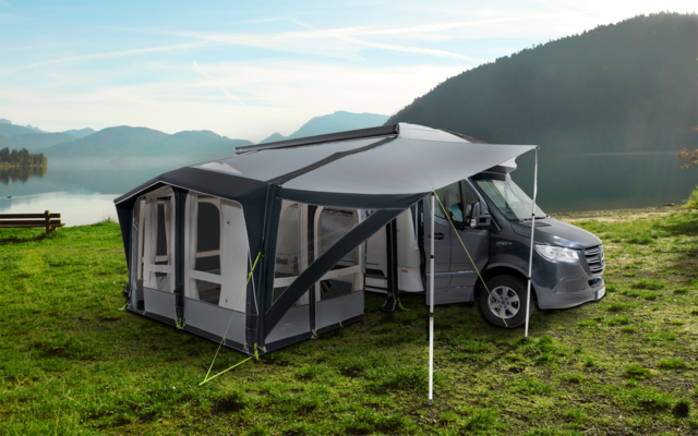 Wohnmobil mit angebautem Vorzelt auf einer Wiese neben einem See