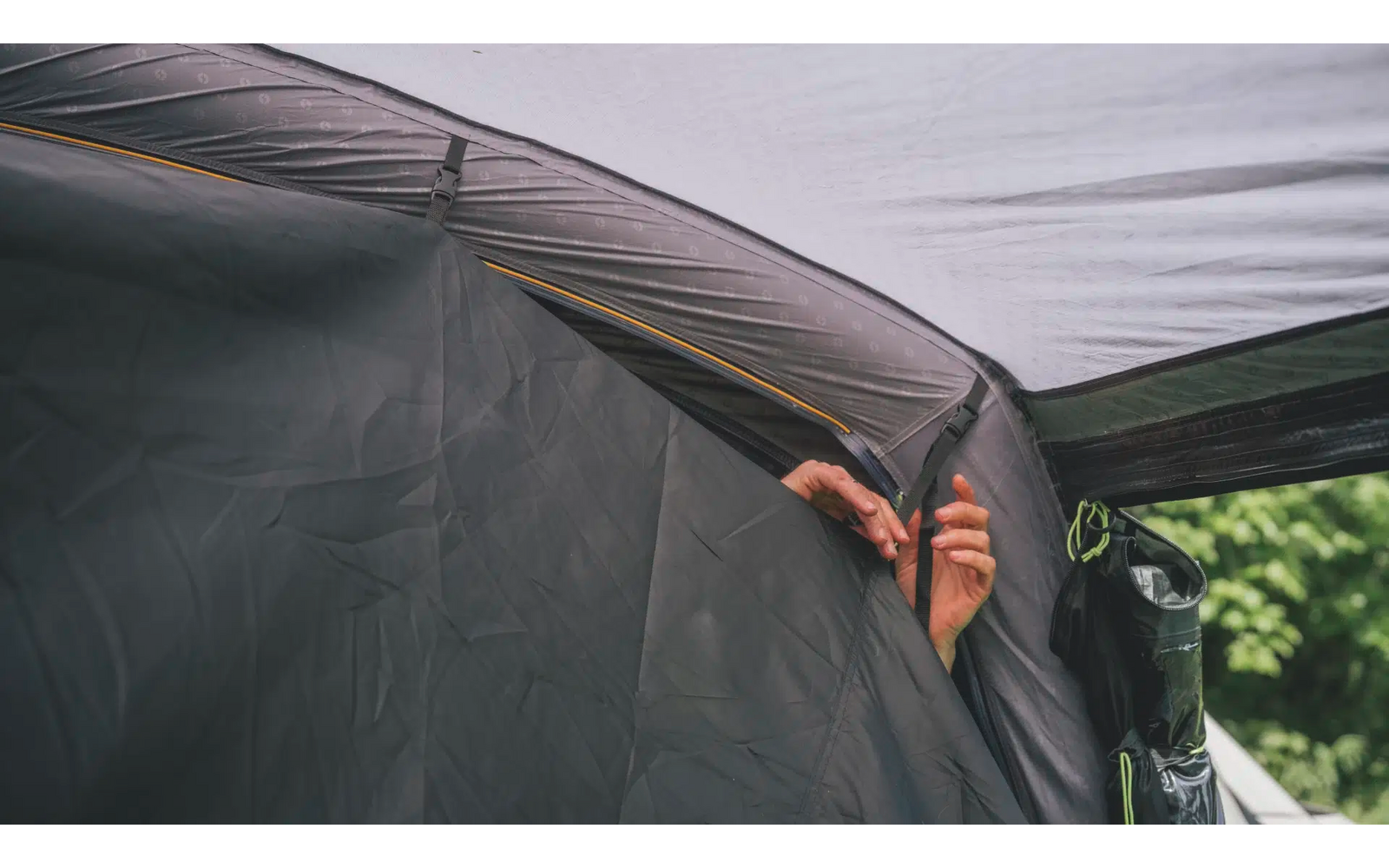 Hand befestigt eine graue Plane an einem Metalldachgestell im Freien