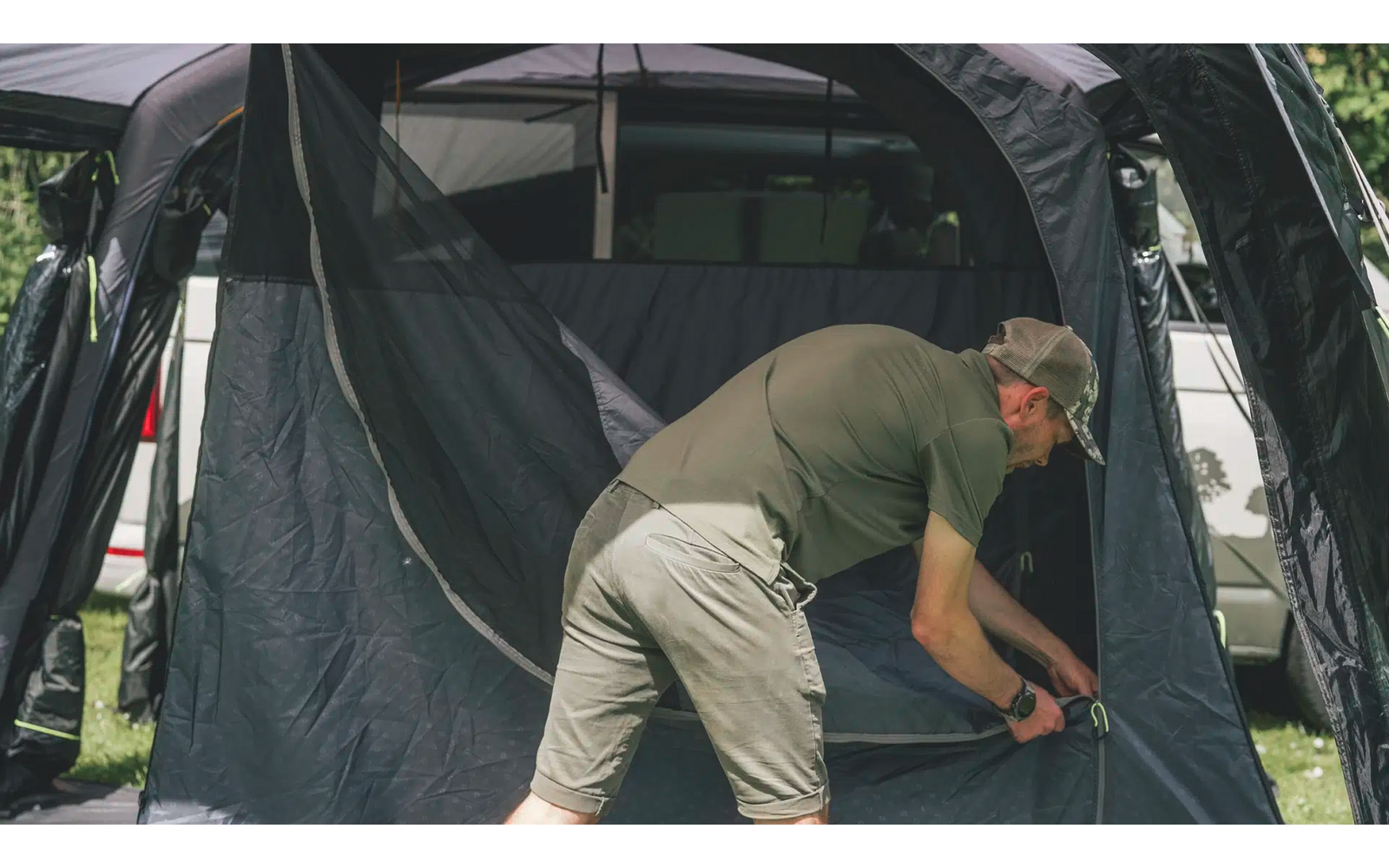 Ein Mann kniet vor einem Zelt und befestigt eine Schnur