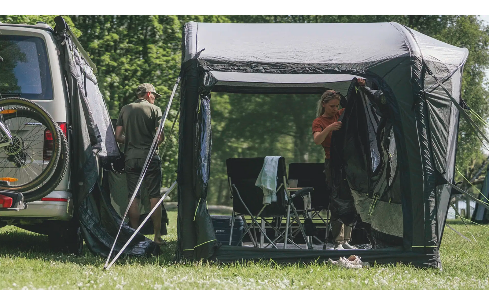 Personen unter einem kleinen schwarzen Pavillon mit einem Tisch und Getränken auf einer Wiese