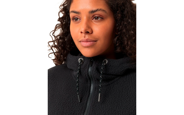 Nahaufnahme eines jungen Frauengesichts mit lockigem Haar, sie trägt einen schwarzen Pullover mit hohem Kragen und Kordelzug