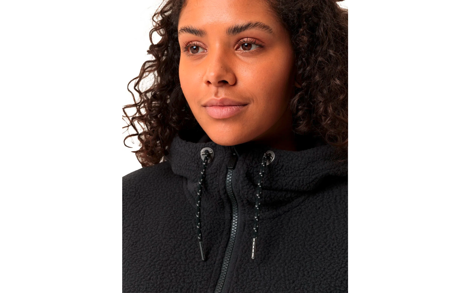 Nahaufnahme eines jungen Frauengesichts mit lockigem Haar, sie trägt einen schwarzen Pullover mit hohem Kragen und Kordelzug