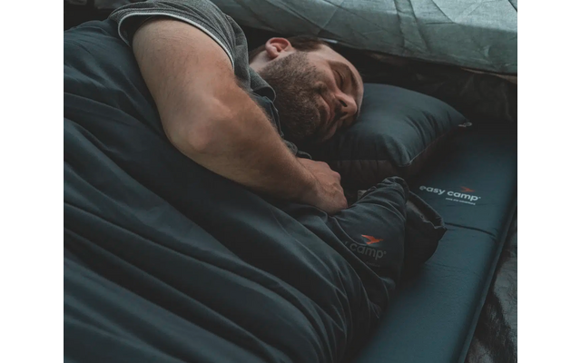 Mann liegt schlafend auf einer Luftmatratze unter einer Decke