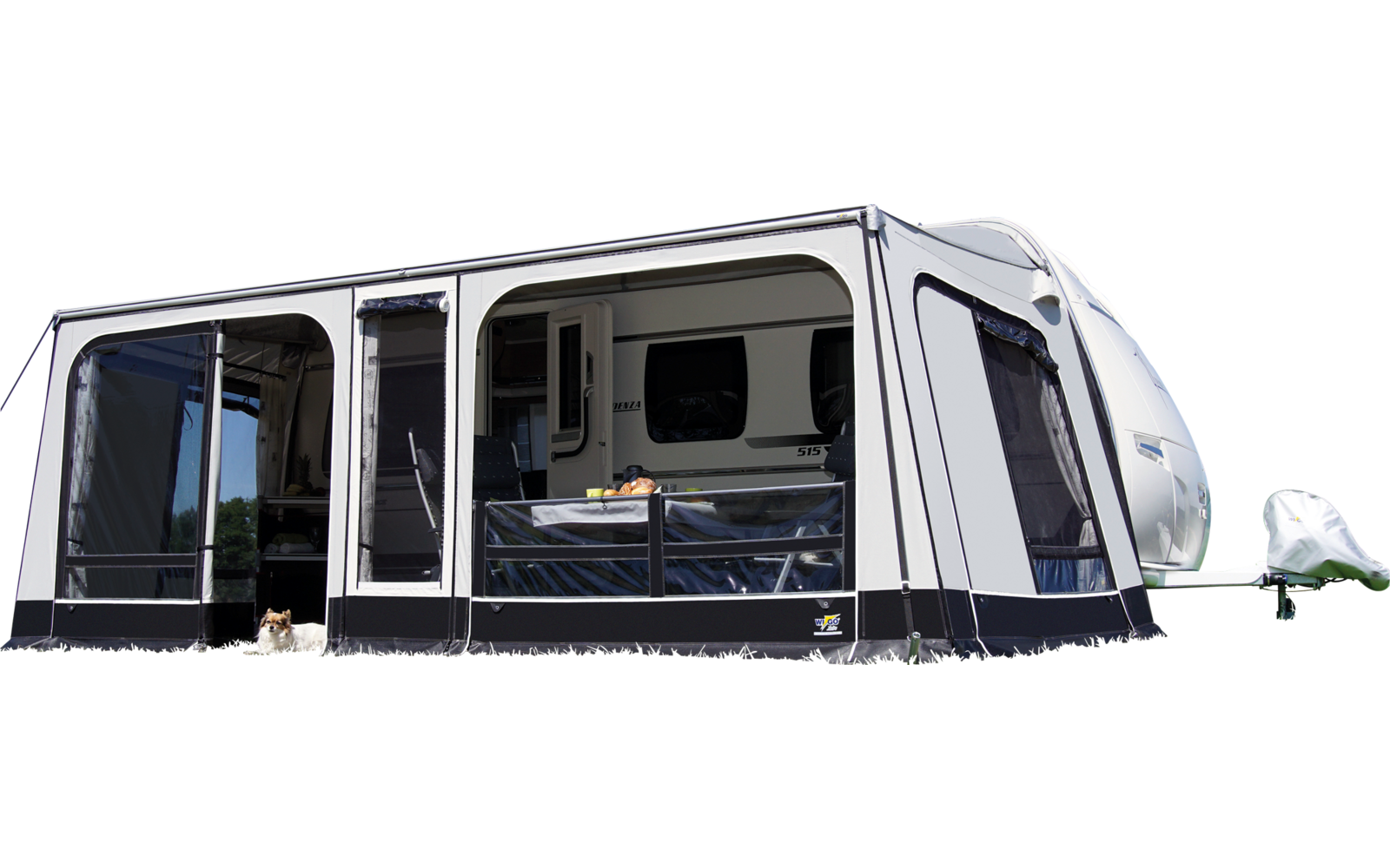 Caravane blanche avec auvent fixé sur une prairie verte sous un ciel bleu