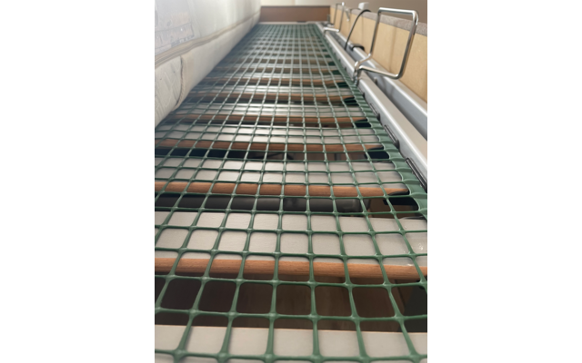 Nahaufnahme eines grünen Netzes über einer Holztreppe in einem Innenraum