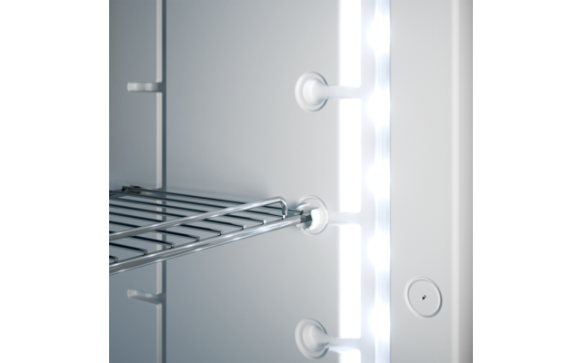 Metallgitterablage vor weißer Innenwand, rechts vertikale Leuchte mit mehreren hellen LEDs, drei runde Kunststoffhalter und eine kleine runde Öffnung