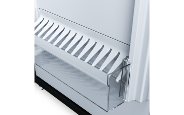 Weiße Innenwand, transparentes Kunststofffach mit Schublade, darüber weißes Regal mit gleichmäßigen schrägen Schlitzen, sichtbares Metallscharnier rechts