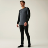 Stehende Person in grauem Langarmshirt mit schwarzen Ärmeln, schwarzen Leggings und schwarzen Socken vor hellem einfarbigem Hintergrund