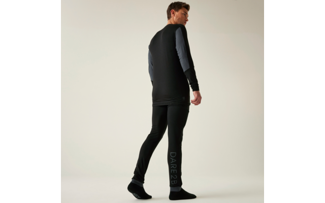 Von hinten sichtbare Person in schwarzem Sport-Langarmshirt und schwarzen Leggings mit hellgrauem "DARE2B"-Schriftzug am linken Bein, schwarze Socken, heller einfarbiger Hintergrund