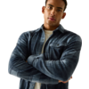 Man met gekruiste armen, blauw geruit overhemd over wit T-shirt, bovenlichaam zichtbaar, kort donker haar