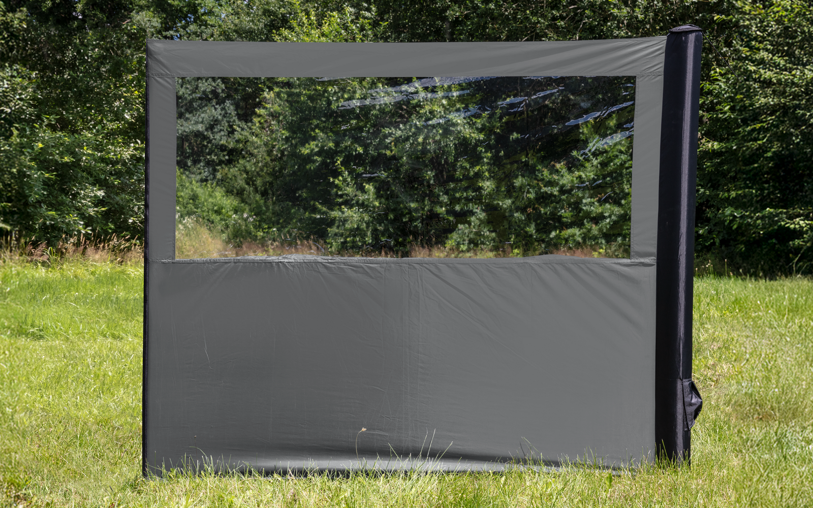 Großes graues winddichtes Schutzschild mit transparentem Fenster auf einer grünen Wiese