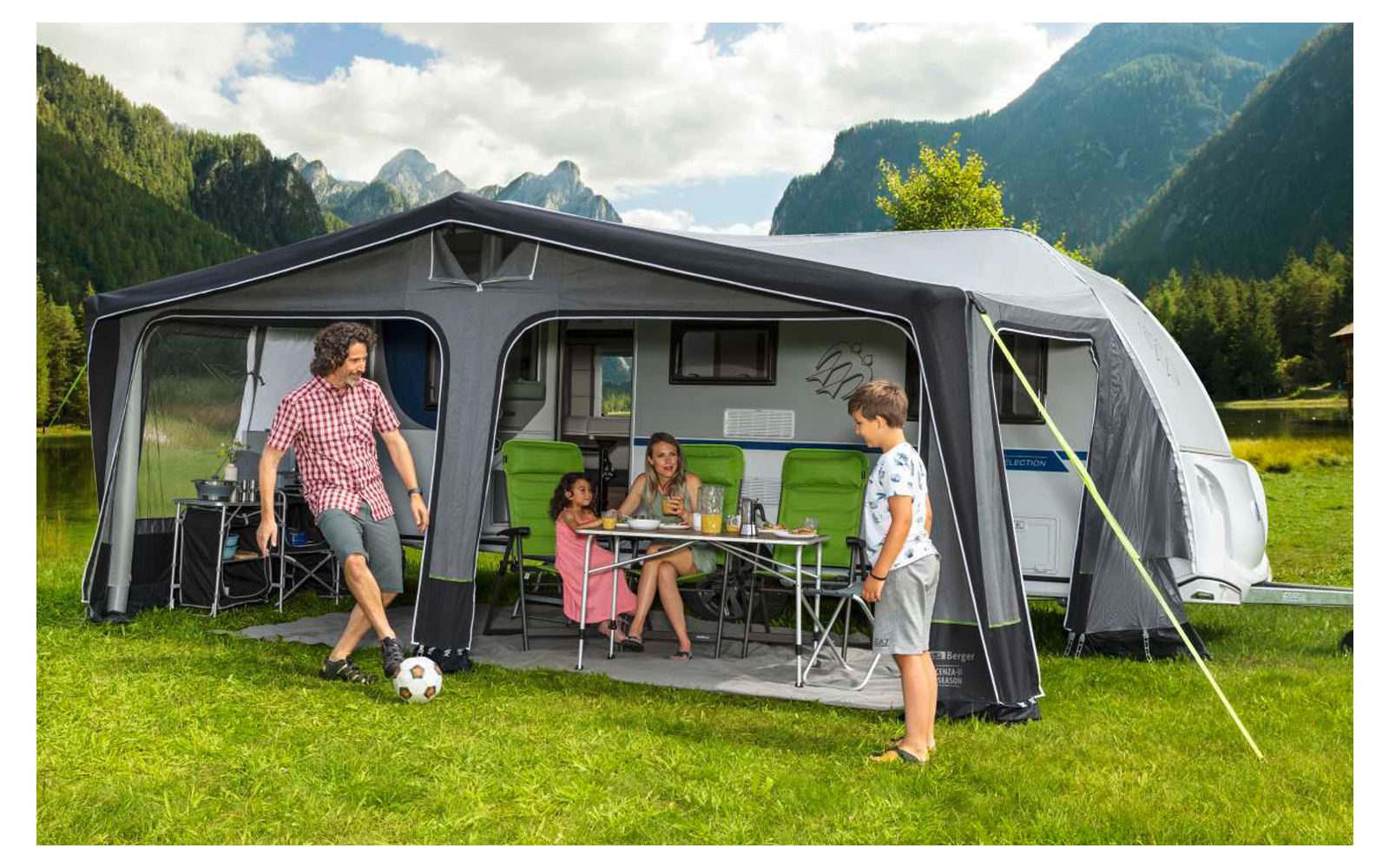 Children playing soccer in front of a caravan in a mountain landscape