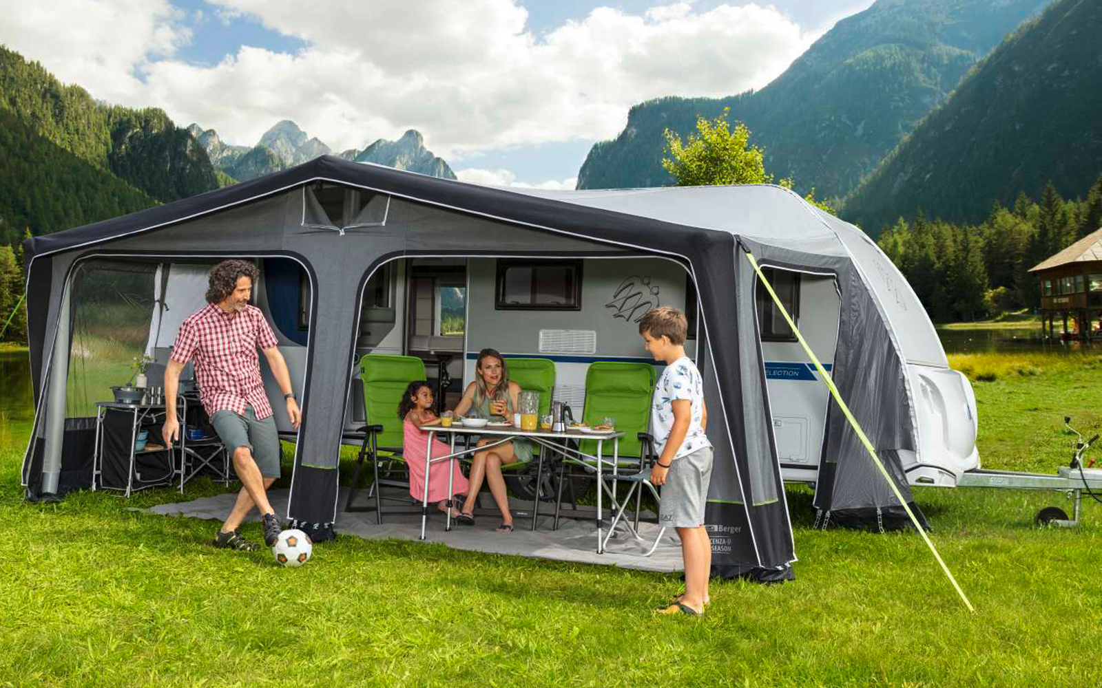 Family with two children in front of a caravan in a mountain landscape