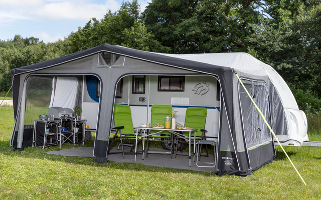 Large white motorhome with attached awning on a green lawn, cloudy sky