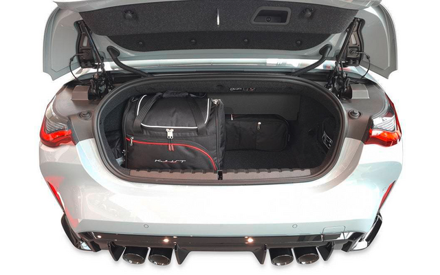 Offener Kofferraum eines weißen Autos mit zwei schwarzen Reisetaschen, sichtbare Rücklichter und vier Auspuffendrohre