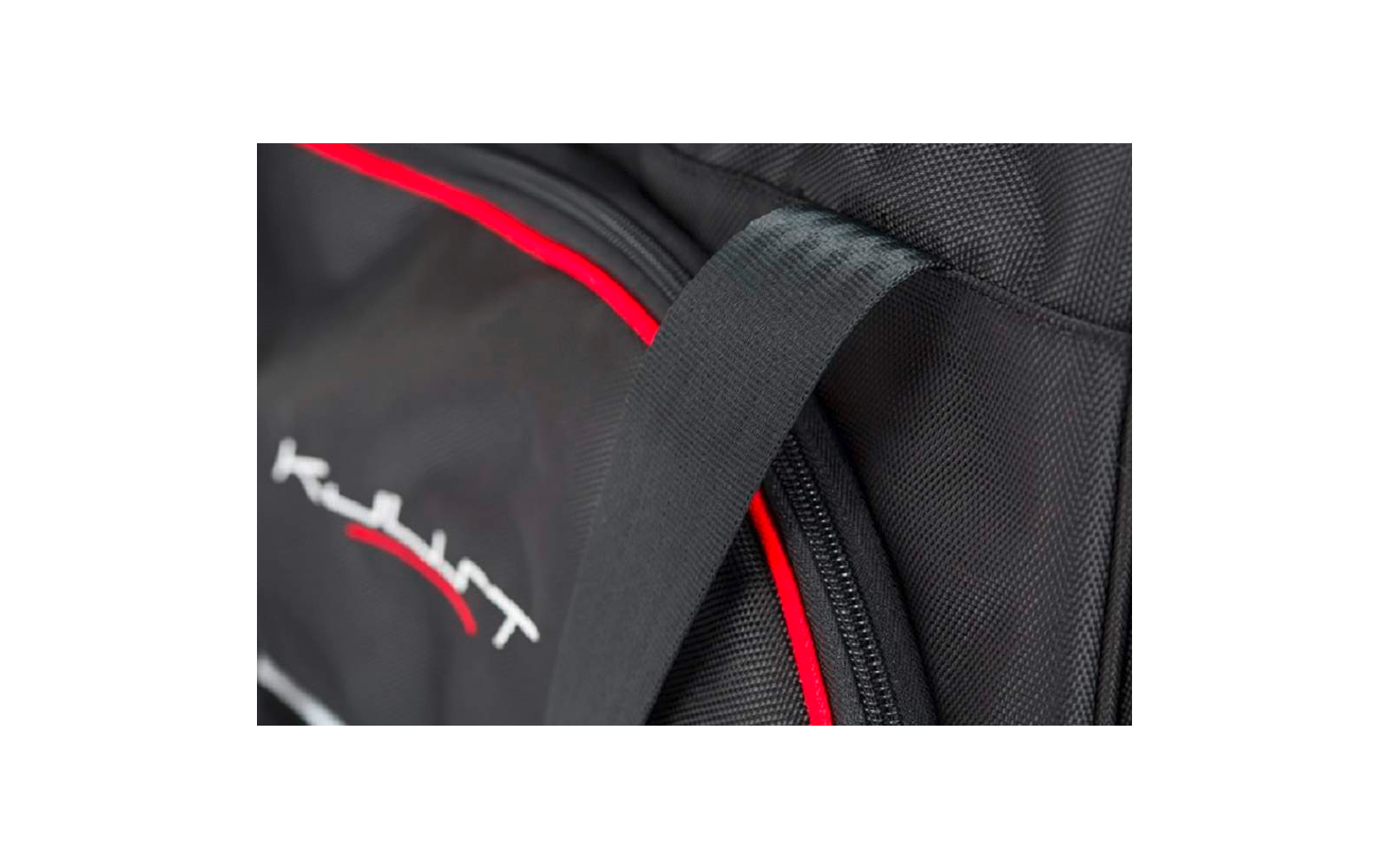 Nahaufnahme einer schwarzen Stofftasche mit schwarzem Tragegurt, Reißverschluss, roter Paspel und weiß-rotem Logo