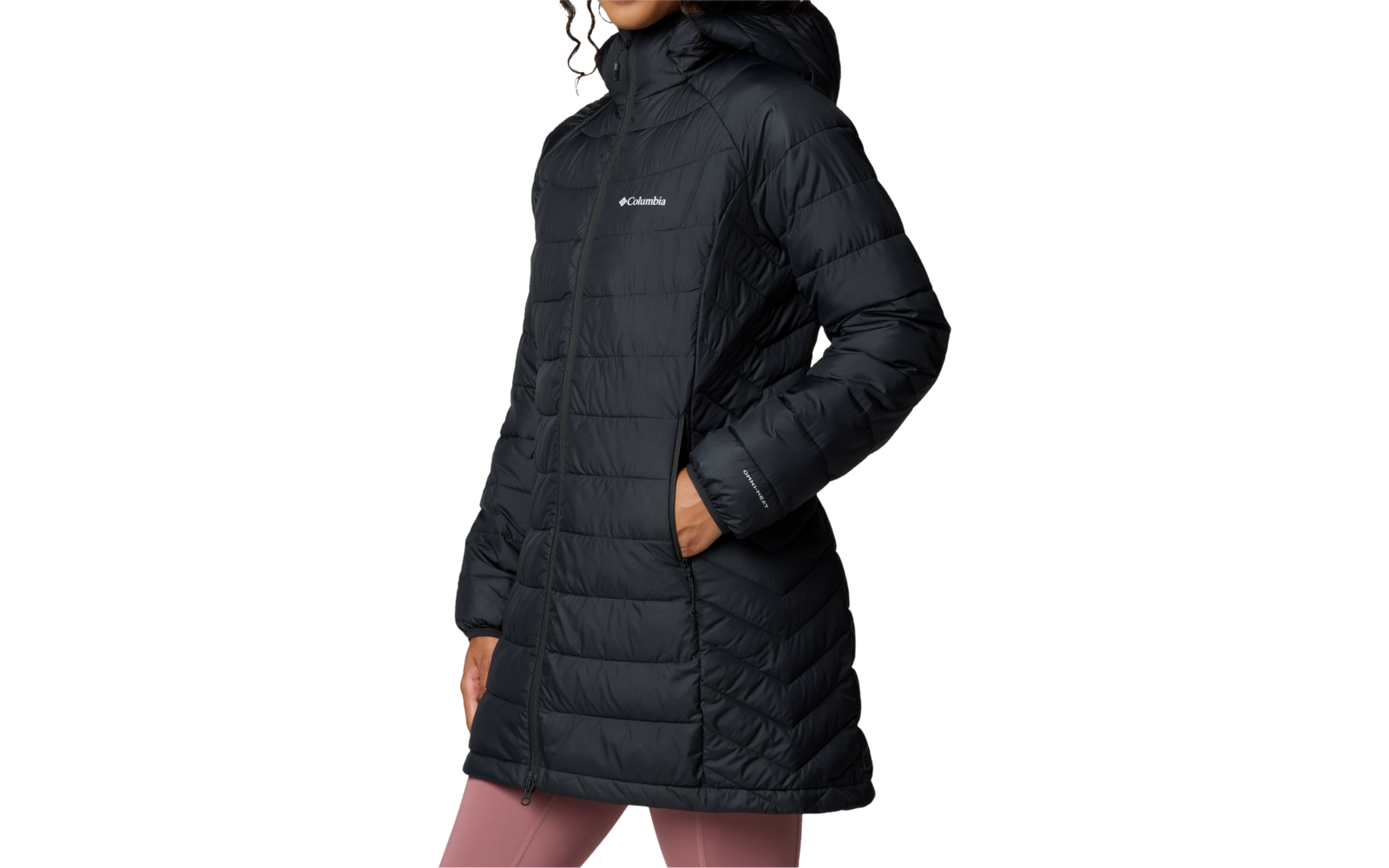 Persoon draagt zwarte, knielange doorgestikte donzen parka met capuchon en zichtbaar "Columbia"-logo, handen in de zakken, roze legging, witte achtergrond