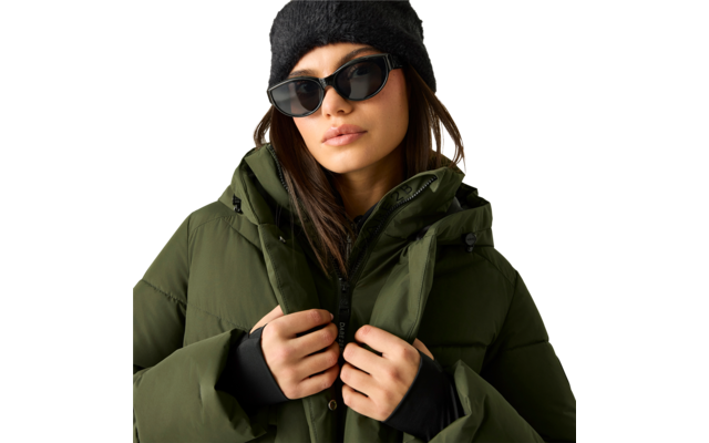 Person mit braunen Haaren, schwarze Mütze und Sonnenbrille, olivgrüne Steppjacke, hält die Jacke am Reißverschluss