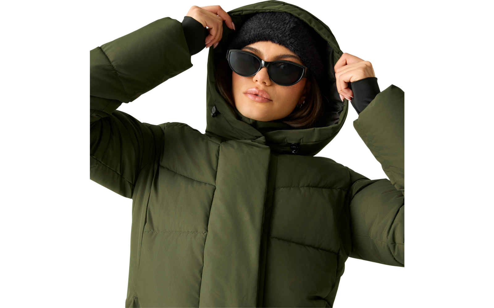 Person mit grüner gesteppter Winterjacke mit Kapuze, schwarzer Mütze und schwarzer Sonnenbrille, hält die Kapuze mit beiden Händen