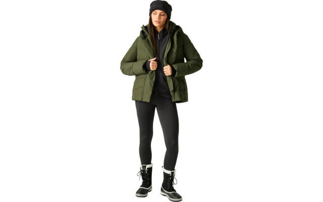 Person steht, trägt grüne gesteppte Winterjacke mit Kapuze, schwarze Strickmütze, schwarzen Reißverschluss-Pullover, schwarze Leggings und schwarze Winterstiefel mit weißem Fellbesatz; Hände halten die Jackenkanten