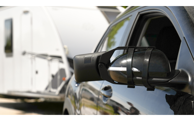 Zwei Männer, die zusammen in einem Wald sitzen und lachen, während einer auf einem großen grauen Stein sitzt und der andere auf dem Boden davor