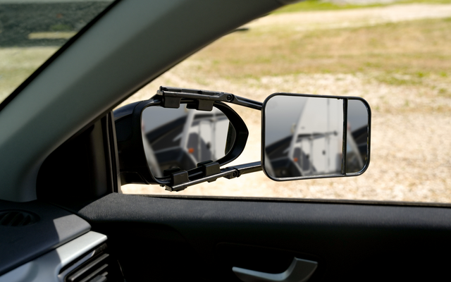 Uitzicht door het open autoruit op de buitenspiegel en een extra rechterspiegel, buiten is een grindoppervlak zichtbaar