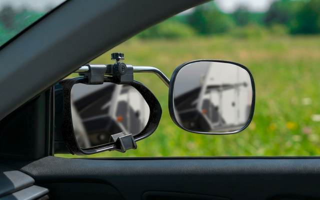 Vista a través de la puerta del conductor de un coche mostrando dos espejos laterales, césped y un camino al fondo