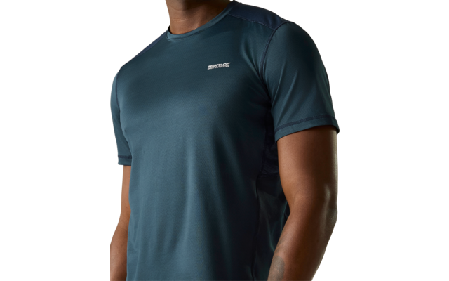 Oberkörper einer Person in kurzärmeligem dunkelgrün-blauem Sportshirt mit rundem Halsausschnitt und kleinem weißen Logo auf der linken Brust; Tattoo am linken Unterarm sichtbar