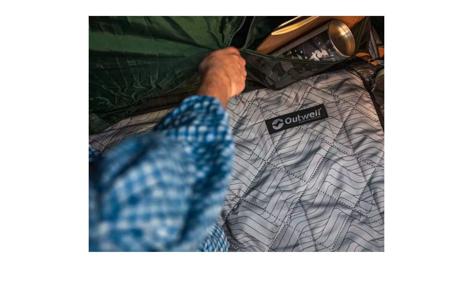 Hand berührt eine graue Daunendecke mit geometrischem Muster