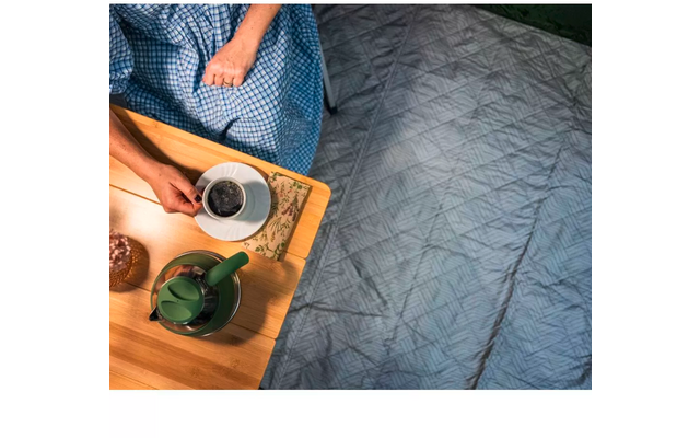 Holztablett mit grünem Teekännchen und weißer Tasse auf grauem Bett