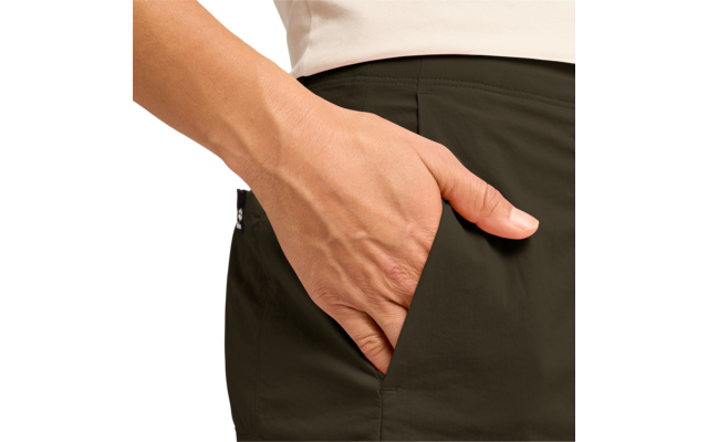 Hand in Hosentasche einer dunkelgrünen Hose, helles Oberteil am Hüftbereich