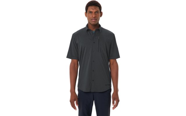 Person mit kurzem dunklem Haar vor weißem Hintergrund, trägt kurzärmeliges dunkel kariertes Hemd mit durchgehender Knopfleiste, Reißverschluss-Brusttasche und dunkle Hosen