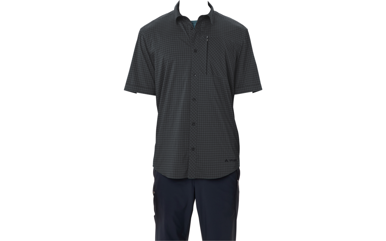 Persona con cabello corto y oscuro de pie sobre fondo blanco, viste una camisa de manga corta oscura con cuadros pequeños, abotonada y con bolsillo con cremallera en el pecho, y pantalones oscuros