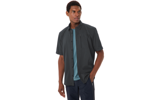 Person trägt dunkel kariertes kurzärmeliges Hemd über türkisfarbenem T-Shirt, Hände in den Taschen, schaut zur Seite vor weißem Hintergrund