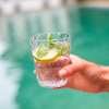 Hand hält ein Glas mit einem Getränk, garniert mit Zitronenscheiben