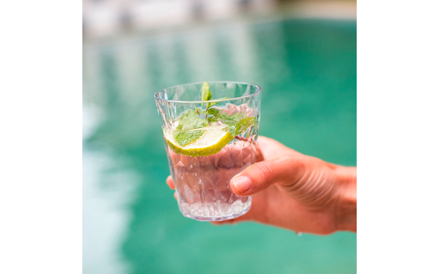 Hand hält ein Glas mit einem Getränk, garniert mit Zitronenscheiben