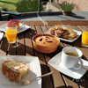 Tisch mit Frühstück im Freien, auf dem verschiedene Getränke, Kaffee und Gebäck stehen