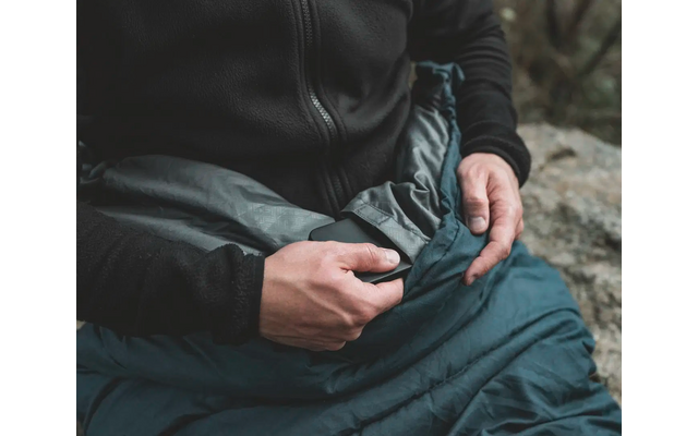 Eine Person, die eine Jacke trägt und beide Hände in ihrem Schoß hält