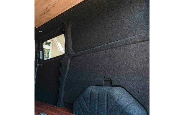 Innenraum eines Kastenwagens mit dunkelgrauer Wandverkleidung, sichtbarem Radkasten, Holzboden und kleinem Seitenfenster links