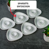 Six white triangular dishes with round recesses on a dark surface; small potted plants at top-left and bottom-right; white rectangle reading 'SPARSETS ENTDECKEN' and a red arrow pointing at one dish