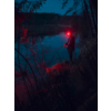 Person mit rotem Licht am Ufer eines Sees bei Nacht