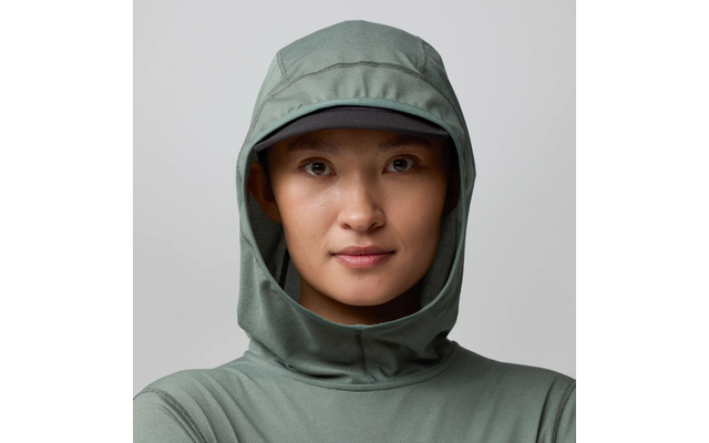 Personne face à l'appareil, visage visible, porte une capuche verte et une casquette sombre