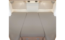 Drei nebeneinander liegende Betten mit beigen Matratzen in einem Wohnmobil