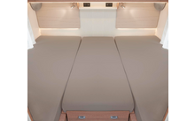 Trois lits côte à côte avec des matelas beiges dans un camping-car