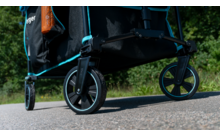 Nahaufnahme von schwarzen Rädern eines Transportwagens auf einem gepflasterten Weg