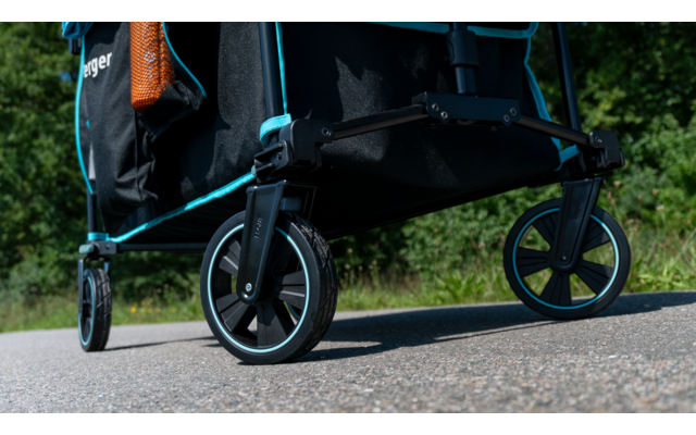 Nahaufnahme von schwarzen Rädern eines Transportwagens auf einem gepflasterten Weg