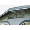 Estructura de tela gris con techo saliente, ventana rectangular transparente con capa de malla y cierres de cremallera, varillas metálicas visibles y dos paneles de tela semicirculares más oscuros debajo