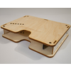 Two stacked light plywood panels with rounded cutouts, rows of small holes, corner slots and visible connecting posts on a white surface