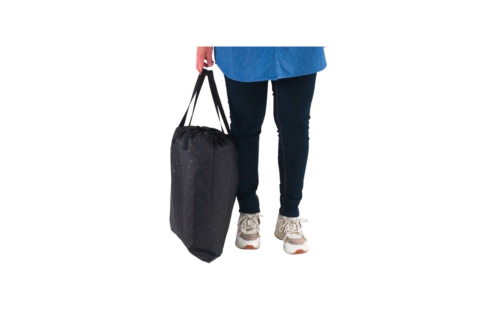 Unterkörper einer Person mit blauem Oberteilsaum, dunkler Hose und Sneakers, Hand hält eine schwarze Tasche seitlich